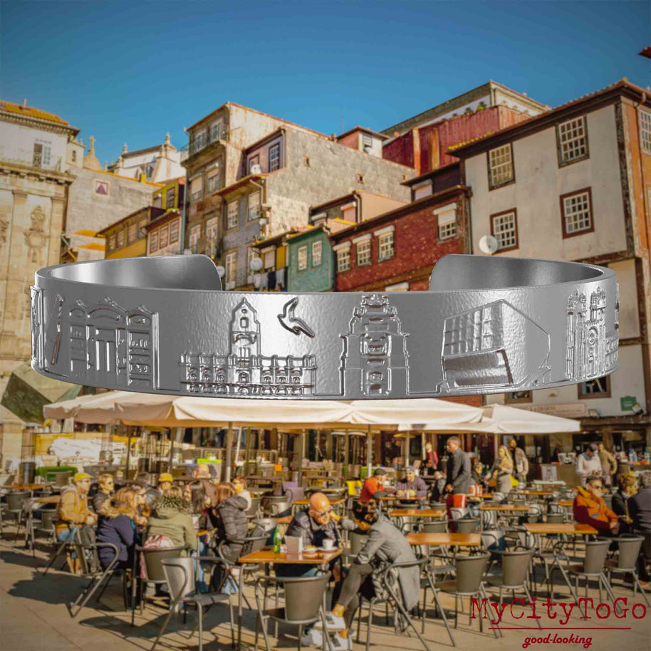 Armreif aus Edelstahl mit Reliefs bekannter Sehenswürdigkeiten der Stadt Porto. Den Hintergrund bildet eine Ansicht der Stadt Porto.