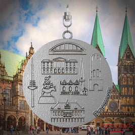 Halskette mit Drehwirbel und Vorderseite eines Schmuckanhängers aus Edelstahl, auf dem Reliefs bekannter Sehenswürdigkeiten der Stadt Bremen abgebildet sind. Den Hintergrund bildet eine Ansicht der Stadt Bremen.
