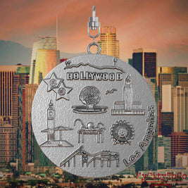 Halskette mit Drehwirbel und Vorderseite eines Schmuckanhängers aus Edelstahl, auf dem Reliefs bekannter Sehenswürdigkeiten der Stadt Los Angeles abgebildet sind. Den Hintergrund bildet eine Ansicht der Stadt Los Angeles.
