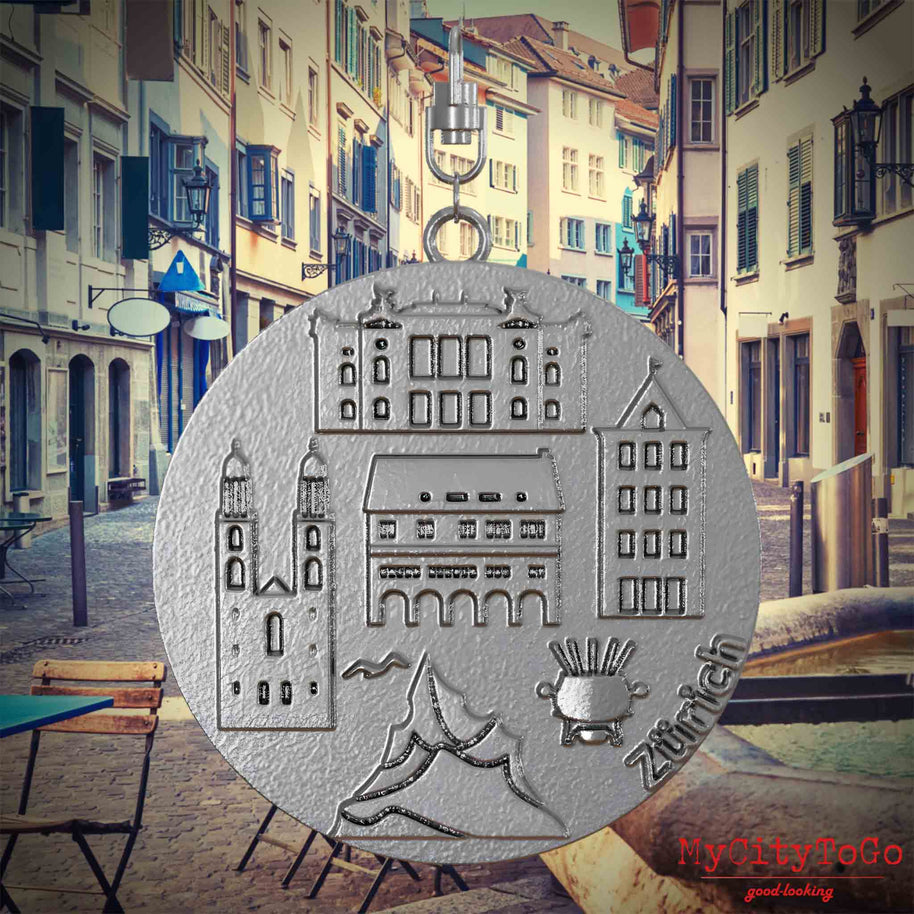 Halskette mit Drehwirbel und Vorderseite eines Schmuckanhängers aus Edelstahl, auf dem Reliefs bekannter Sehenswürdigkeiten der Stadt Zuerich abgebildet sind. Den Hintergrund bildet eine Ansicht der Stadt Zuerich.
