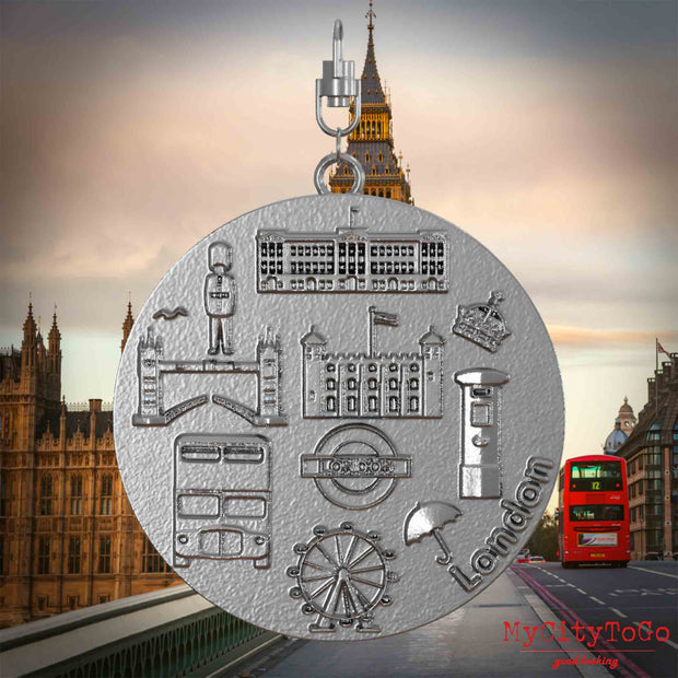 Halskette mit Drehwirbel und Vorderseite eines Schmuckanhängers aus Edelstahl, auf dem Reliefs bekannter Sehenswürdigkeiten der Stadt London abgebildet sind. Den Hintergrund bildet eine Ansicht der Stadt London.
