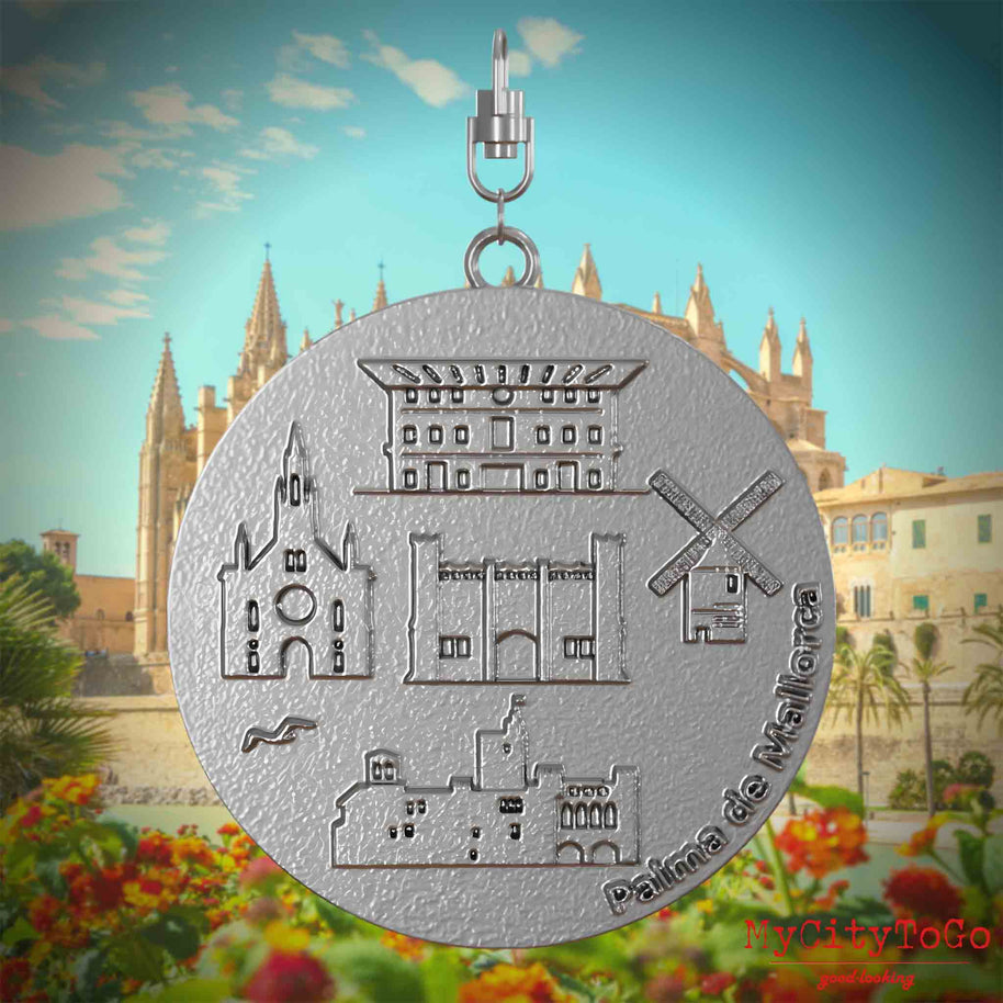 Halskette mit Drehwirbel und Vorderseite eines Schmuckanhängers aus Edelstahl, auf dem Reliefs bekannter Sehenswürdigkeiten der Stadt Palma de Mallorca abgebildet sind. Den Hintergrund bildet eine Ansicht der Stadt Palma de Mallorca.
