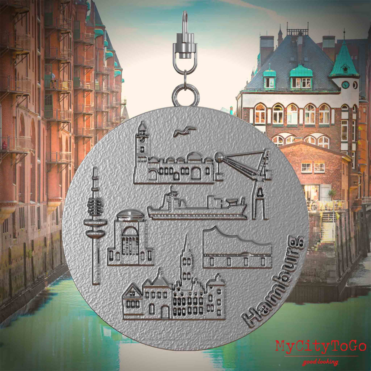 Halskette mit Drehwirbel und Rückseite eines Schmuckanhängers aus Edelstahl, auf dem Reliefs bekannter Sehenswürdigkeiten der Stadt Hamburg abgebildet sind. Den Hintergrund bildet eine Ansicht der Stadt Hamburg.