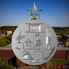 Halskette mit Drehwirbel und Rückseite eines Schmuckanhängers aus Edelstahl, auf dem Reliefs bekannter Sehenswürdigkeiten der Stadt Bochum abgebildet sind. Den Hintergrund bildet eine Ansicht der Stadt Bochum .
