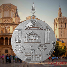 Halskette mit Drehwirbel und Vorderseite eines Schmuckanhängers aus Edelstahl, auf dem Reliefs bekannter Sehenswürdigkeiten der Stadt Valencia abgebildet sind. Den Hintergrund bildet eine Ansicht der Stadt Valencia.
