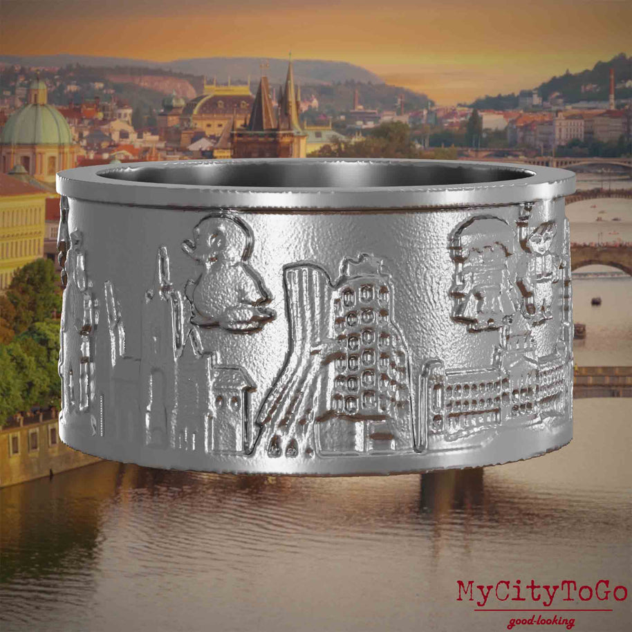Ring aus Edelstahl mit Reliefs bekannter Sehenswürdigkeiten der Stadt Prag. Den Hintergrund bildet eine Ansicht der Stadt Prag.