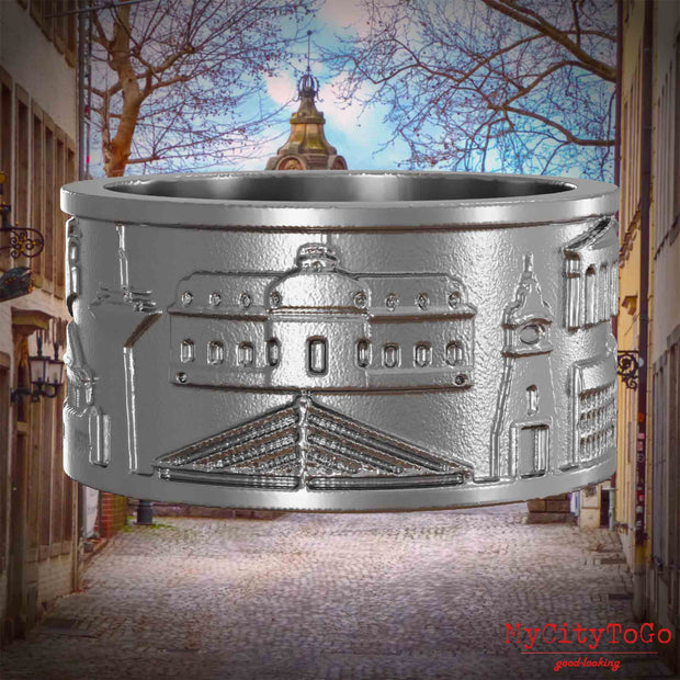 Ring aus Edelstahl mit Reliefs bekannter Sehenswürdigkeiten der Stadt Duesseldorf. Den Hintergrund bildet eine Ansicht der Stadt Duesseldorf.