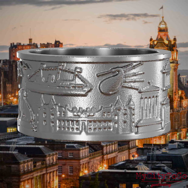 Ring aus Edelstahl mit Reliefs bekannter Sehenswürdigkeiten der Stadt Edinburgh. Den Hintergrund bildet eine Ansicht der Stadt Edinburgh.