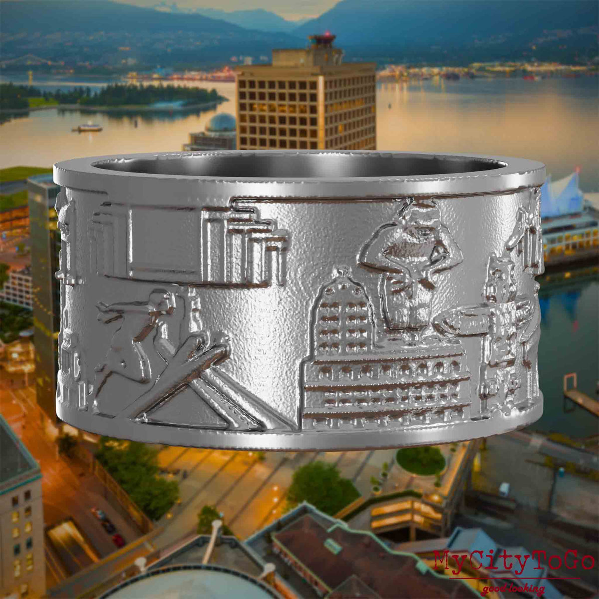 Ring aus Edelstahl mit Reliefs bekannter Sehenswürdigkeiten der Stadt Vancouver. Den Hintergrund bildet eine Ansicht der Stadt Vancouver.