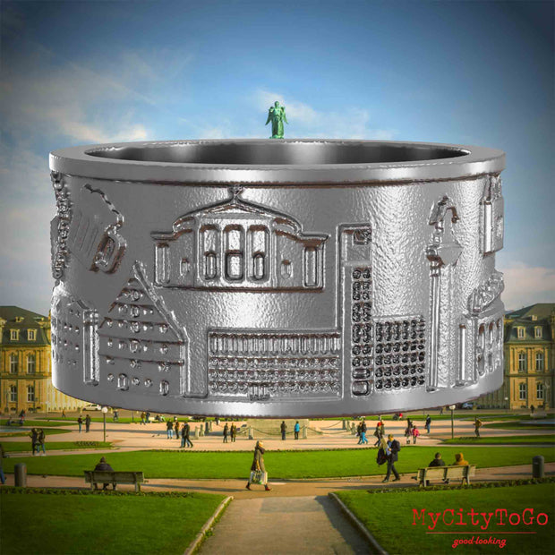 Ring aus Edelstahl mit Reliefs bekannter Sehenswürdigkeiten der Stadt Stuttgart. Den Hintergrund bildet eine Ansicht der Stadt Stuttgart.