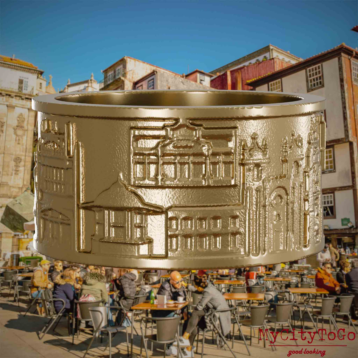 Ring aus vergoldetem Edelstahl mit Reliefs bekannter Sehenswürdigkeiten der Stadt Porto. Den Hintergrund bildet eine Ansicht der Stadt Porto.