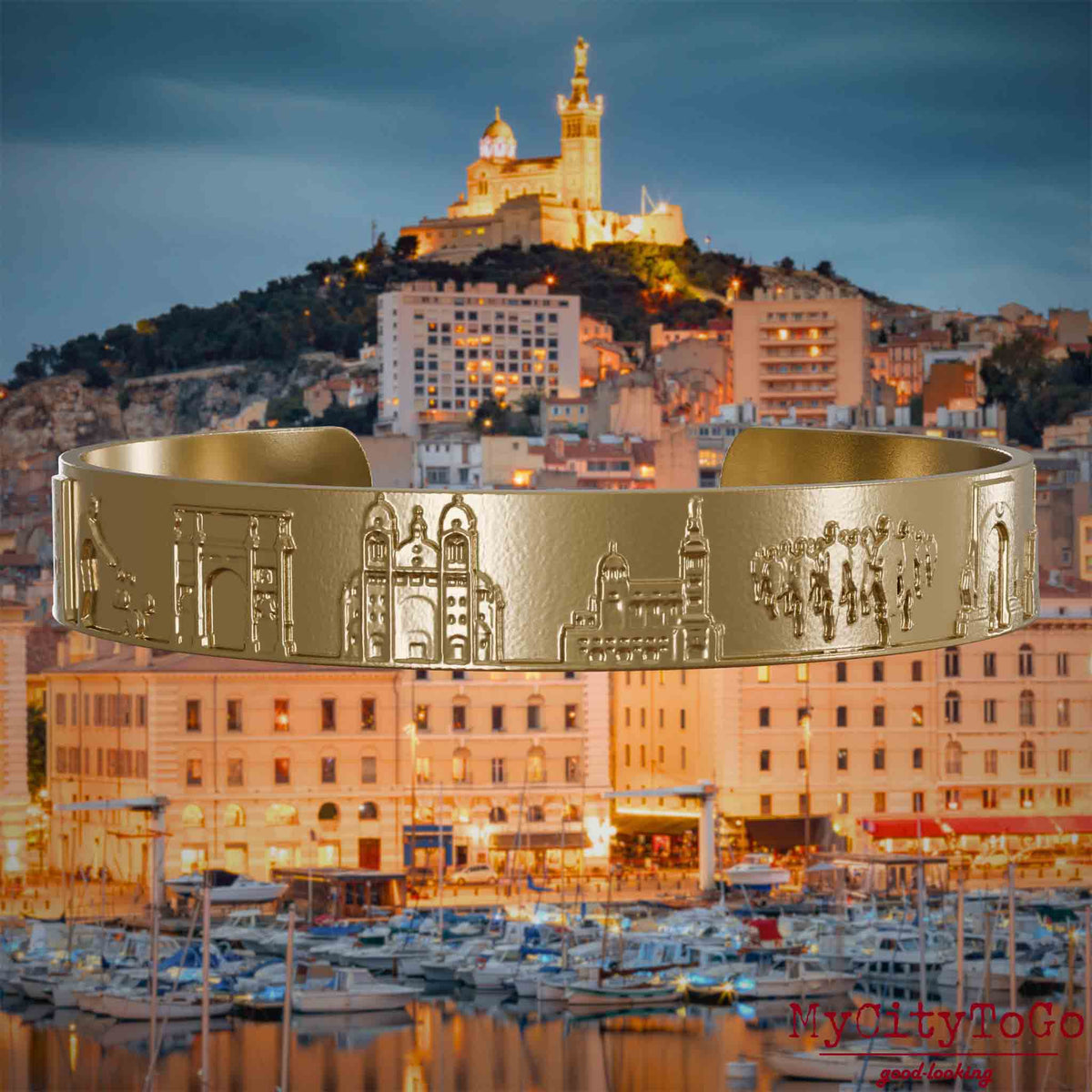 Armreif aus vergoldetem Edelstahl mit Reliefs bekannter Sehenswürdigkeiten der Stadt Marseille. Den Hintergrund bildet eine Ansicht der Stadt Marseille.