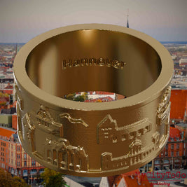 Ring aus vergoldetem Edelstahl mit Reliefs bekannter Sehenswürdigkeiten der Stadt Hannover und einer Gravur des Stadtnamens auf der Innenseite. Den Hintergrund bildet eine Ansicht der Stadt Hannover.