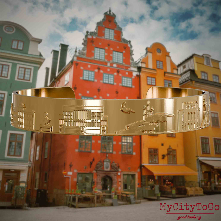 Vergoldeter Armreif mit Reliefs bekannter Sehenswürdigkeiten der Stadt Stockholm. Den Hintergrund bildet eine Ansicht der Stadt Stockholm.