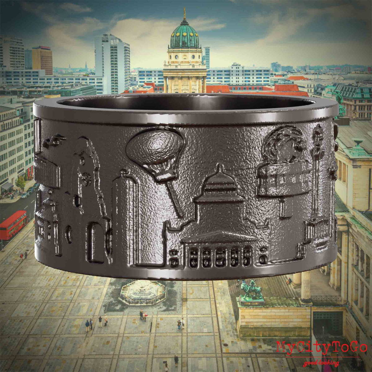 Ring aus Titan mit Reliefs bekannter Sehenswürdigkeiten der Stadt Berlin. Den Hintergrund bildet eine Ansicht der Stadt Berlin. 