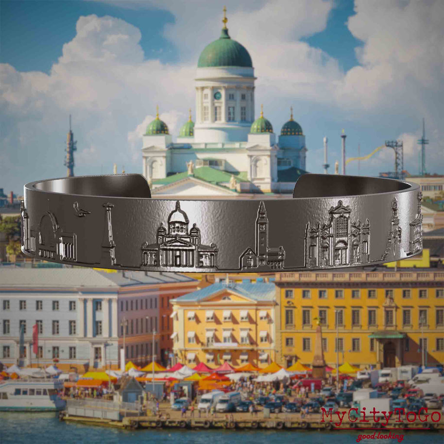 Armreif aus Titan mit Reliefs bekannter Sehenswürdigkeiten der Stadt Helsinki. Den Hintergrund bildet eine Ansicht der Stadt Helsinki.