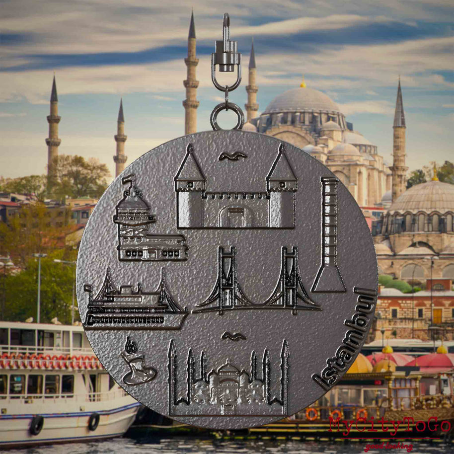 Halskette mit Drehwirbel und Vorderseite eines Schmuckanhängers aus Titan, auf dem Reliefs bekannter Sehenswürdigkeiten der Stadt Istanbul abgebildet sind. Den Hintergrund bildet eine Ansicht der Stadt Istanbul.
