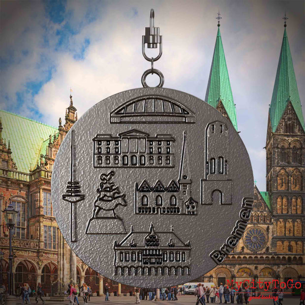 Halskette mit Drehwirbel und Vorderseite eines Schmuckanhängers aus Titan, auf dem Reliefs bekannter Sehenswürdigkeiten der Stadt Bremen abgebildet sind. Den Hintergrund bildet eine Ansicht der Stadt Bremen.