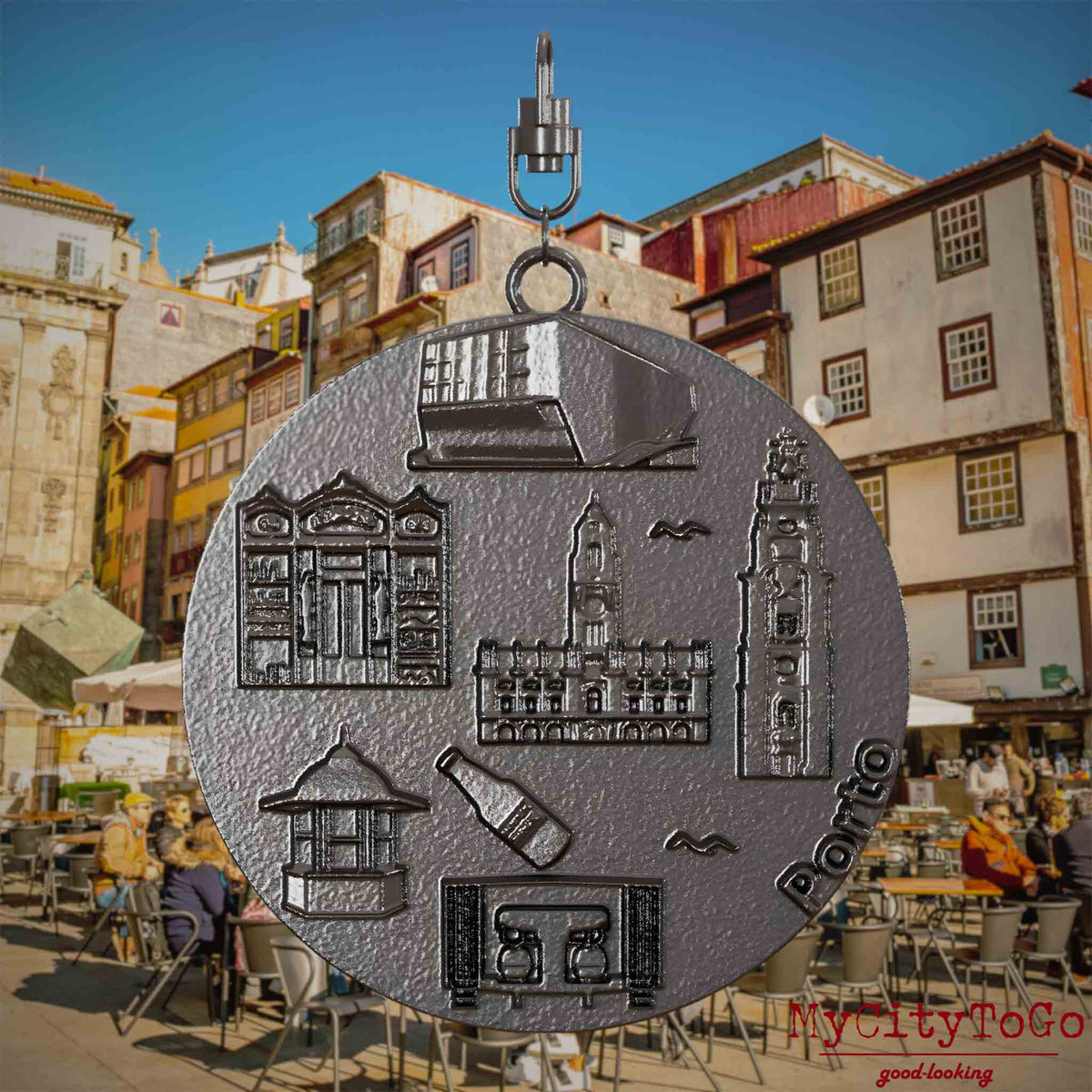 Halskette mit Drehwirbel und Vorderseite eines Schmuckanhängers aus Titan, auf dem Reliefs bekannter Sehenswürdigkeiten der Stadt Porto abgebildet sind. Den Hintergrund bildet eine Ansicht der Stadt Porto.
