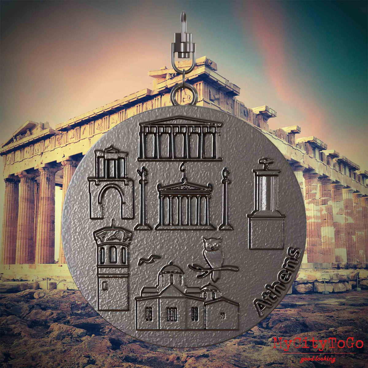 Halskette mit Drehwirbel und Rückseite eines Schmuckanhängers aus Titan, auf dem Reliefs bekannter Sehenswürdigkeiten der Stadt Athen abgebildet sind. Den Hintergrund bildet eine Ansicht der Stadt Athen.
