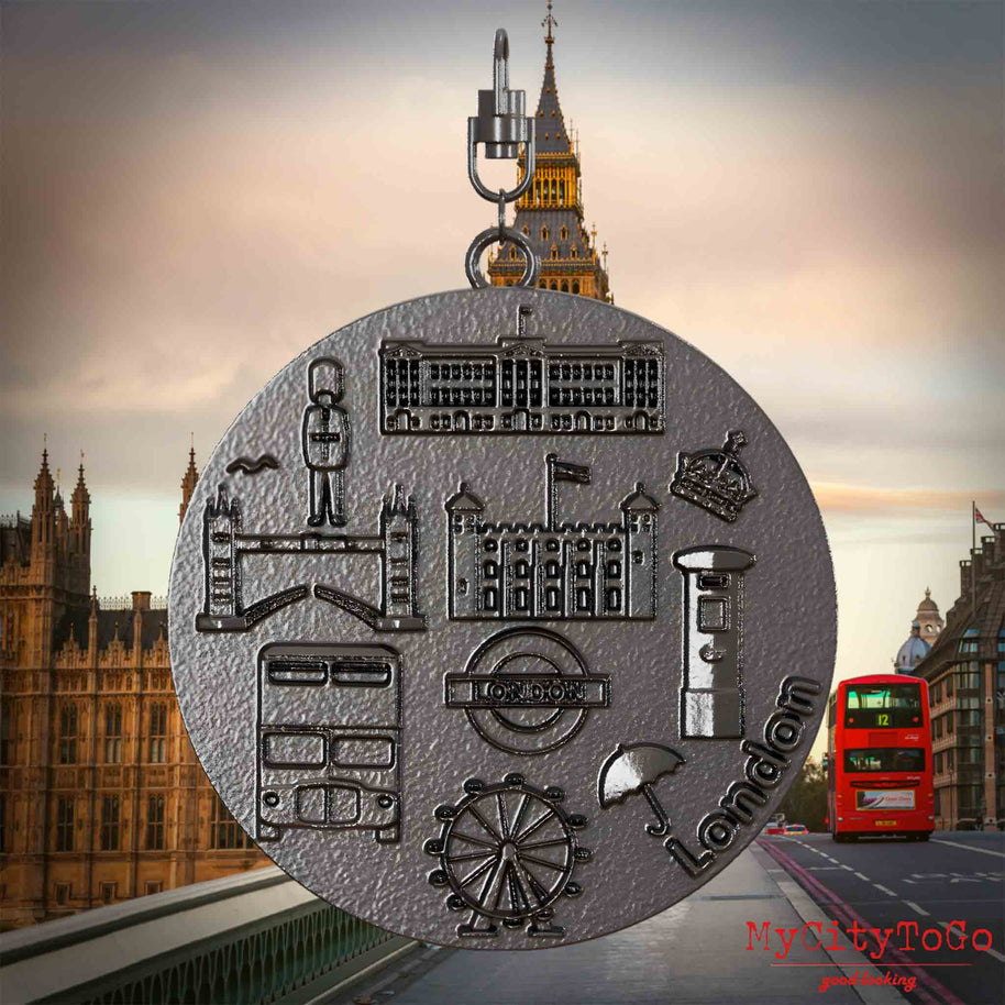Halskette mit Drehwirbel und Vorderseite eines Schmuckanhängers aus Titan, auf dem Reliefs bekannter Sehenswürdigkeiten der Stadt London abgebildet sind. Den Hintergrund bildet eine Ansicht der Stadt London.
