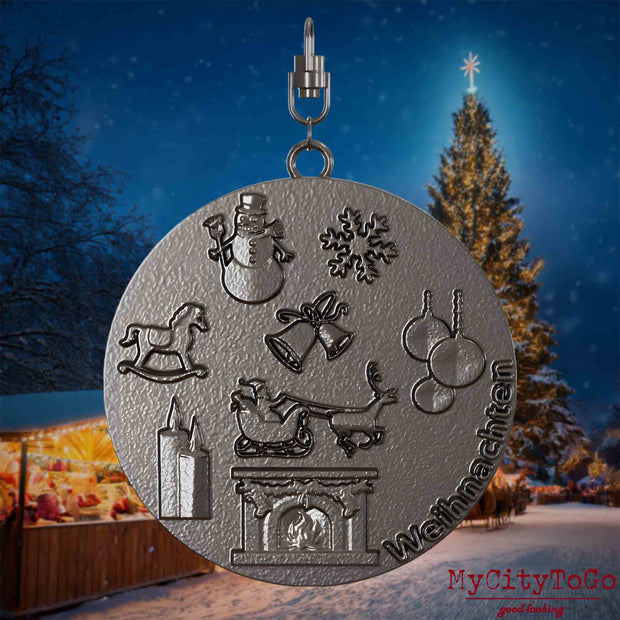Halskette mit Drehwirbel und Vorderseite eines Schmuckanhängers aus Titan, auf dem Reliefs bekannter Weihnachst- und Wintermotive abgebildet sind. Den Hintergrund bildet ein naechtliches Weihnachtsmotiv.
