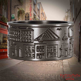 Ring aus Titan mit Reliefs bekannter Sehenswürdigkeiten der Stadt Dublin. Den Hintergrund bildet eine Ansicht der Stadt Dublin.