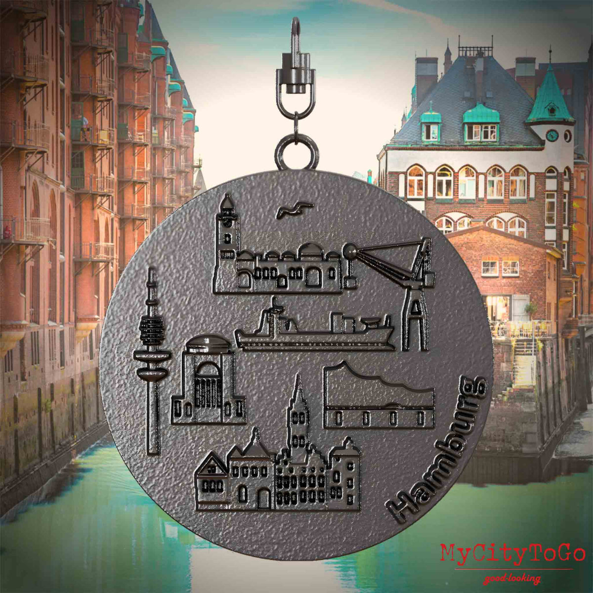Halskette mit Drehwirbel und Rückseite eines Schmuckanhängers aus Titan, auf dem Reliefs bekannter Sehenswürdigkeiten der Stadt Hamburg abgebildet sind. Den Hintergrund bildet eine Ansicht der Stadt Hamburg.