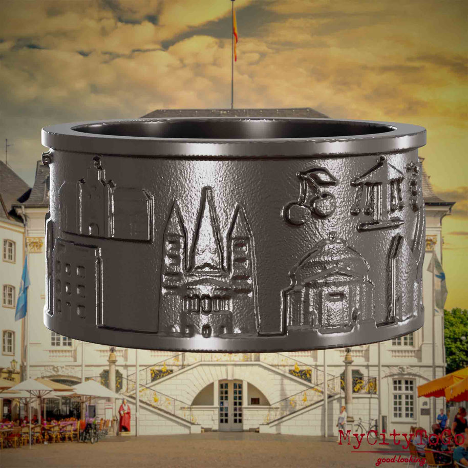 Ring aus Titan mit Reliefs bekannter Sehenswürdigkeiten der Stadt Bonn. Den Hintergrund bildet eine Ansicht der Stadt Bonn.