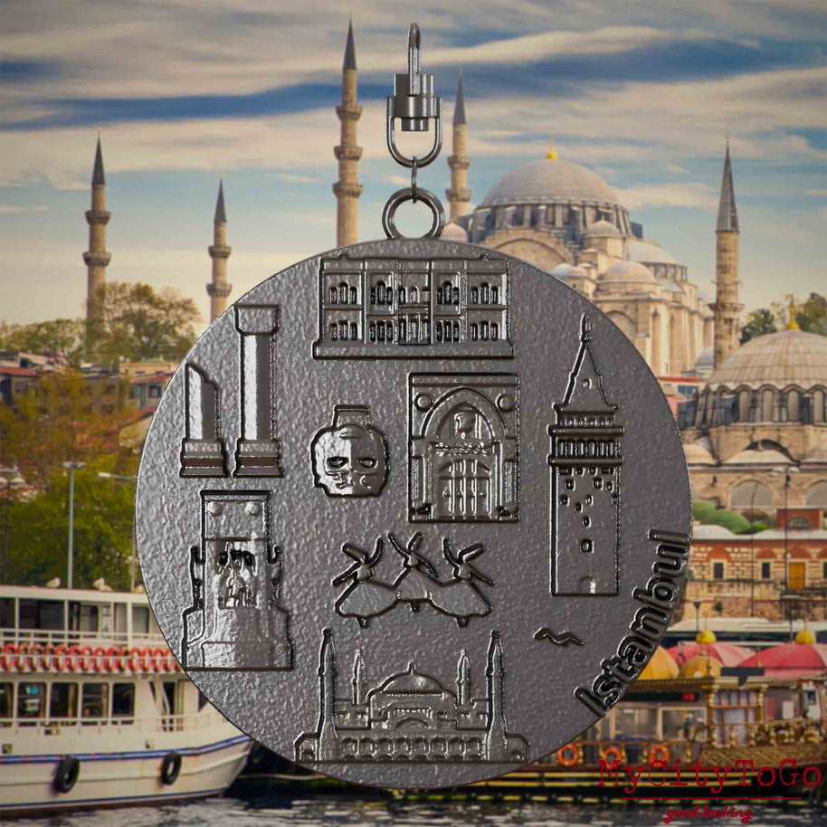 Halskette mit Drehwirbel und Rückseite eines Schmuckanhängers aus Titan, auf dem Reliefs bekannter Sehenswürdigkeiten der Stadt Istanbul abgebildet sind. Den Hintergrund bildet eine Ansicht der Stadt Istanbul.

