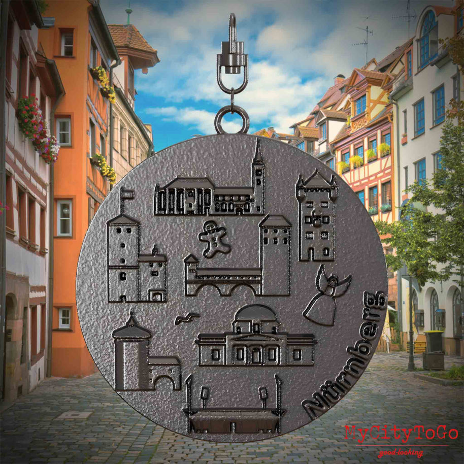 Halskette mit Drehwirbel und Rückseite eines Schmuckanhängers aus Titan, auf dem Reliefs bekannter Sehenswürdigkeiten der Stadt Nuernberg abgebildet sind. Den Hintergrund bildet eine Ansicht der Stadt Nuernberg.