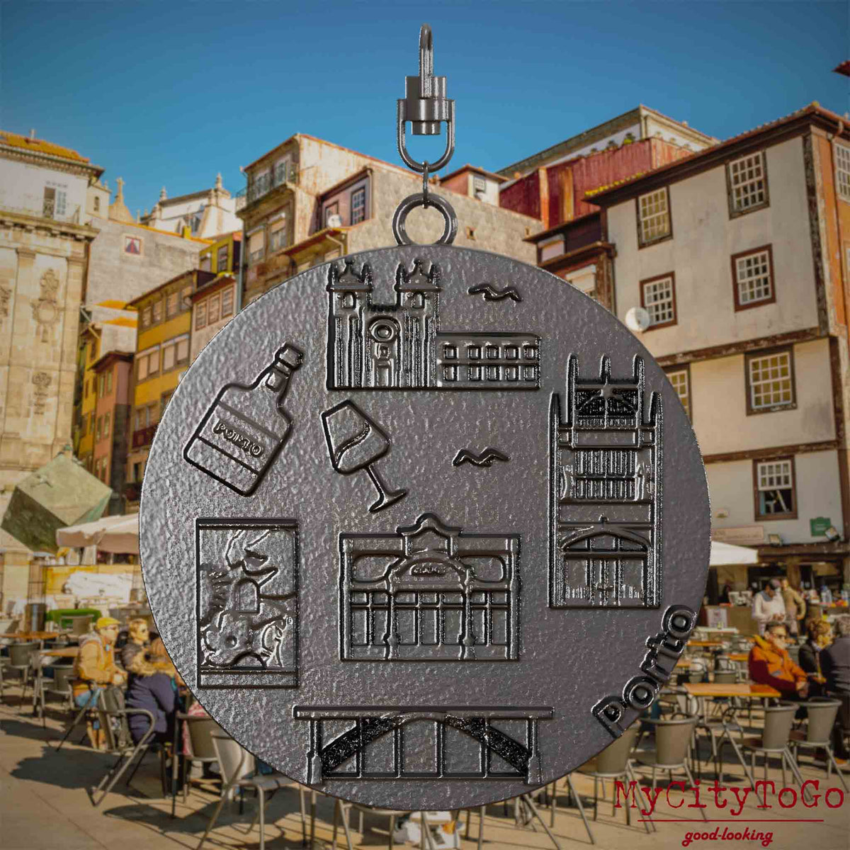 Halskette mit Drehwirbel und Rückseite eines Schmuckanhängers aus Titan, auf dem Reliefs bekannter Sehenswürdigkeiten der Stadt Porto abgebildet sind. Den Hintergrund bildet eine Ansicht der Stadt Porto.
