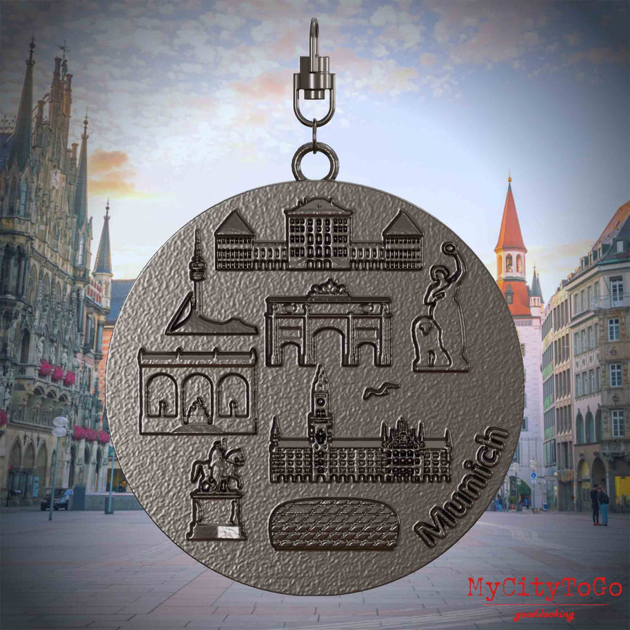 Halskette mit Drehwirbel und Rückseite eines Schmuckanhängers aus Titan, auf dem Reliefs bekannter Sehenswürdigkeiten der Stadt Muenchen abgebildet sind. Den Hintergrund bildet eine Ansicht der Stadt Muenchen.