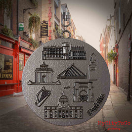Halskette mit Drehwirbel und Rückseite eines Schmuckanhängers aus Titan, auf dem Reliefs bekannter Sehenswürdigkeiten der Stadt Dublin abgebildet sind. Den Hintergrund bildet eine Ansicht der Stadt Dublin.
