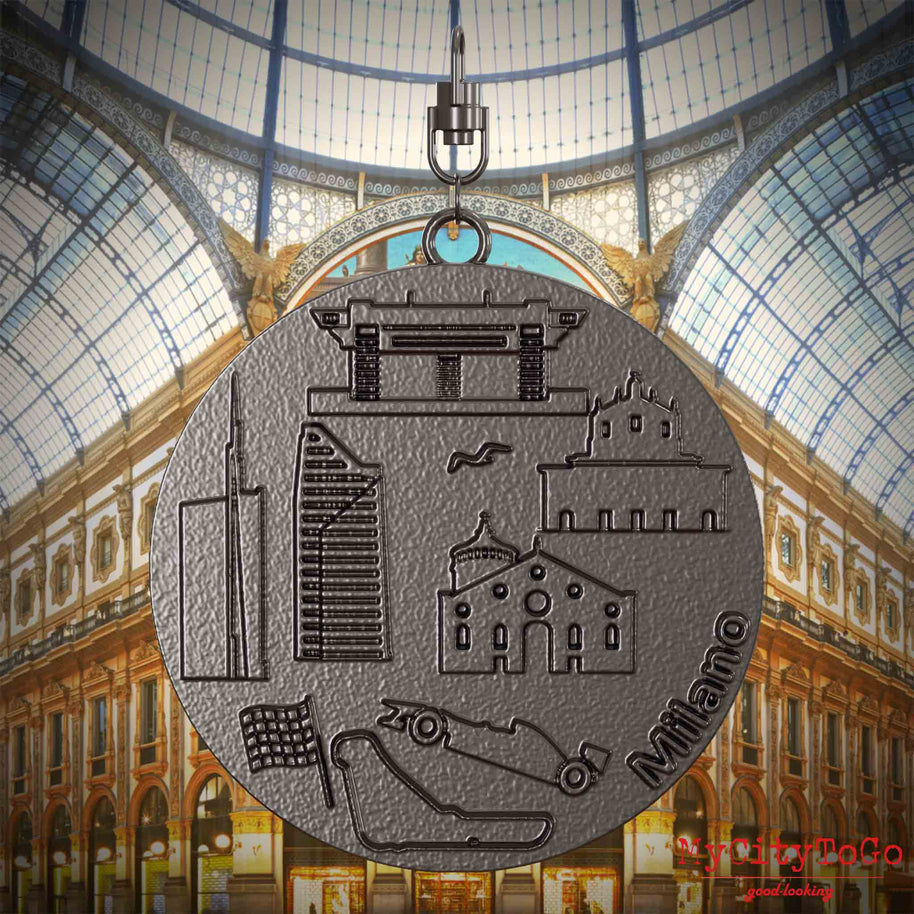 Halskette mit Drehwirbel und Vorderseite eines Schmuckanhängers aus Titan, auf dem Reliefs bekannter Sehenswürdigkeiten der Stadt Mailand abgebildet sind. Den Hintergrund bildet eine Ansicht der Stadt Mailand.
