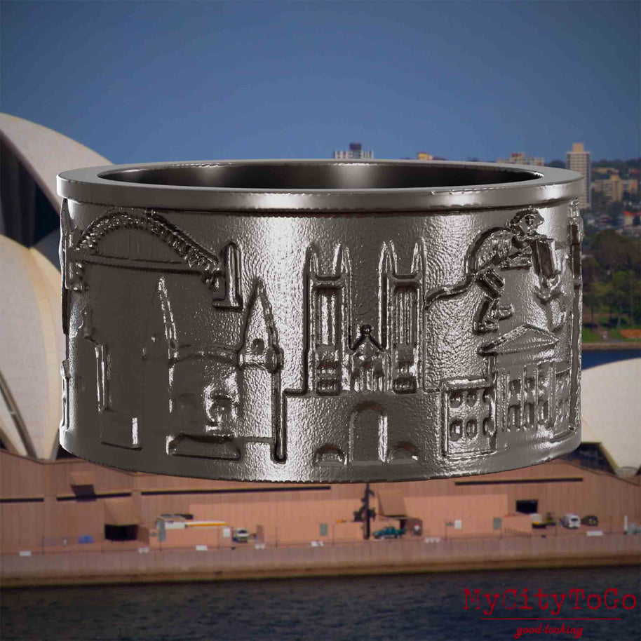 Ring aus Titan mit Reliefs bekannter Sehenswürdigkeiten der Stadt Sydney. Den Hintergrund bildet eine Ansicht der Stadt Sydney.