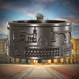 Ring aus Titan mit Reliefs bekannter Sehenswürdigkeiten der Stadt Dresden. Den Hintergrund bildet eine Ansicht der Stadt Dresden.