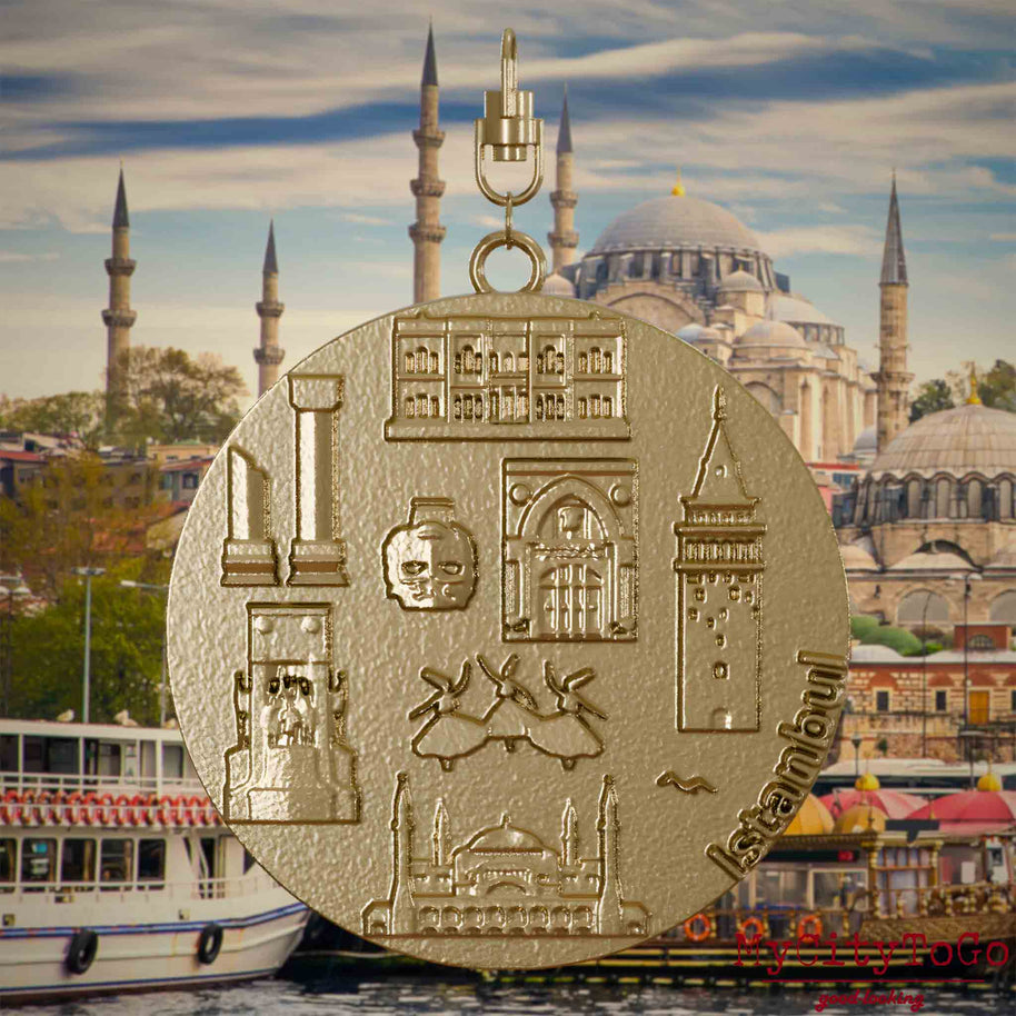 Halskette mit Drehwirbel und Rückseite eines Schmuckanhängers aus vergoldetem Edelstahl, auf dem Reliefs bekannter Sehenswürdigkeiten der Stadt Istanbul abgebildet sind. Den Hintergrund bildet eine Ansicht der Stadt Istanbul.
