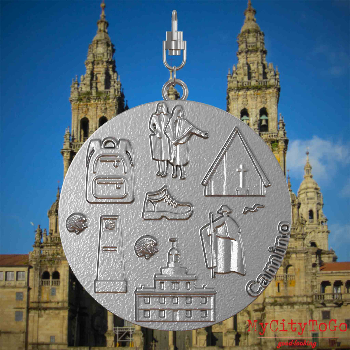 Halskette mit Drehwirbel und Vorderseite eines Schmuckanhängers aus Edelstahl, auf dem Reliefs bekannter Sehenswürdigkeiten des Jakobswegs abgebildet sind. Den Hintergrund bildet eine Ansicht der Stadt Santiago de compostela.
