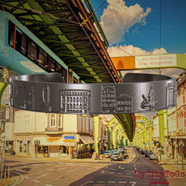 Armreif aus Titan mit Reliefs bekannter Sehenswürdigkeiten der Stadt Wuppertal. Den Hintergrund bildet eine Ansicht  der Stadt Wuppertal.