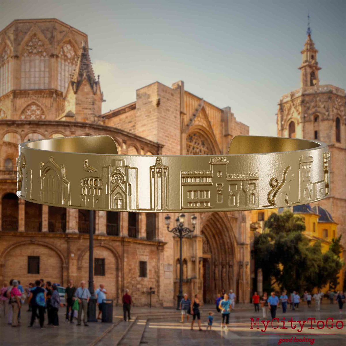 Armreif aus vergoldetem Edelstahl mit Reliefs bekannter Sehenswürdigkeiten der Stadt Valencia. Den Hintergrund bildet eine Ansicht der Stadt Valencia.