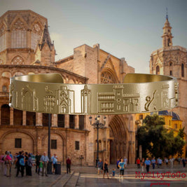 Armreif aus vergoldetem Edelstahl mit Reliefs bekannter Sehenswürdigkeiten der Stadt Valencia. Den Hintergrund bildet eine Ansicht der Stadt Valencia.
