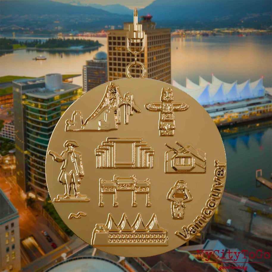 Halskette mit Drehwirbel und Vorderseite eines vergoldeten Schmuckanhängers, auf dem Reliefs bekannter Sehenswürdigkeiten der Stadt Vancouver abgebildet sind. Den Hintergrund bildet eine Ansicht der Stadt Vancouver.
