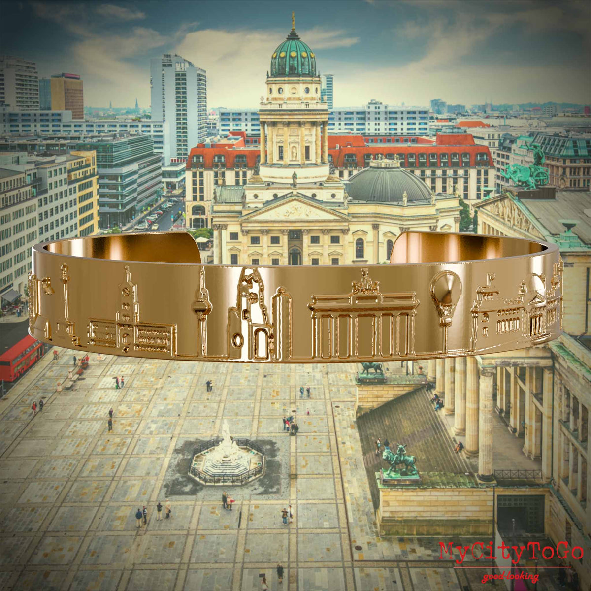 Vergoldeter Armreif mit Reliefs bekannter Sehenswürdigkeiten der Stadt Berlin. Den Hintergrund bildet eine Ansicht der Stadt Berlin. 