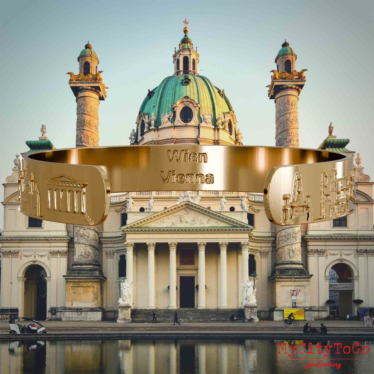Innenseite eines vergoldeten Armreifs mit Reliefs bekannter Sehenswürdigkeiten der Stadt Wien und einer Gravur des Stadtnamens . Den Hintergrund bildet eine Ansicht der Stadt Wien.