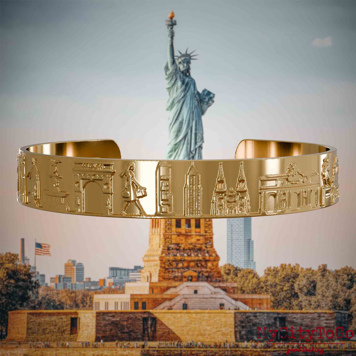 Vergoldeter Armreif mit Reliefs bekannter Sehenswürdigkeiten der Stadt New York. Den Hintergrund bildet eine Ansicht der Stadt New York.