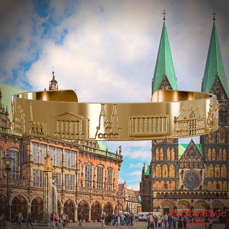 Vergoldeter Armreif mit Reliefs bekannter Motive der Stadt Bremen. Den Hintergrund bildet eine Ansicht der Stadt Bremen.
