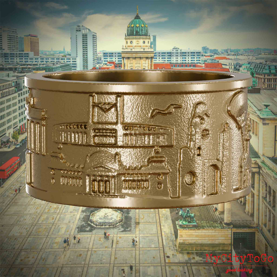 Ring aus vergoldetem Edelstahl mit Reliefs bekannter Sehenswürdigkeiten der Stadt Berlin. Den Hintergrund bildet eine Ansicht der Stadt Berlin. 