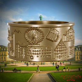 Ring aus vergoldetem Edelstahl mit Reliefs bekannter Sehenswürdigkeiten der Stadt Stuttgart. Den Hintergrund bildet eine Ansicht der Stadt Stuttgart.