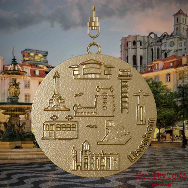 Halskette mit Drehwirbel und Vorderseite eines Schmuckanhängers aus vergoldetem Edelstahl, auf dem Reliefs bekannter Sehenswürdigkeiten der Stadt Lissabon abgebildet sind. Den Hintergrund bildet eine Ansicht der Stadt Lissabon.
